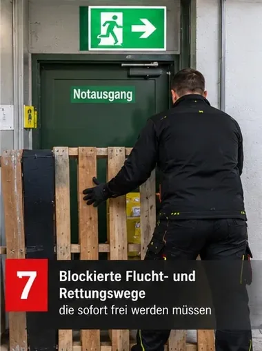 Blockierte Flucht- und Rettungswege, die sofort frei werden müssen – Mitarbeiter räumt Paletten vor einem Notausgang weg