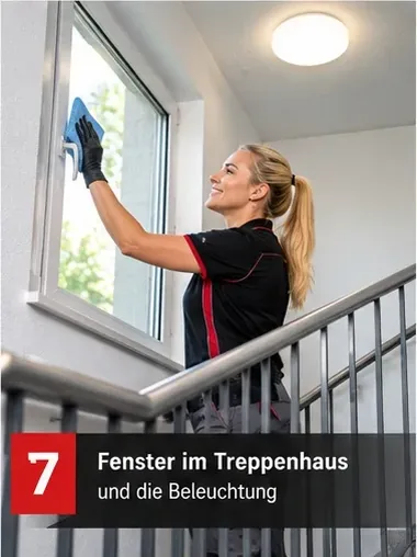 Fenster im Treppenhaus und die Beleuchtung – Mitarbeiterin reinigt ein Treppenhausfenster
